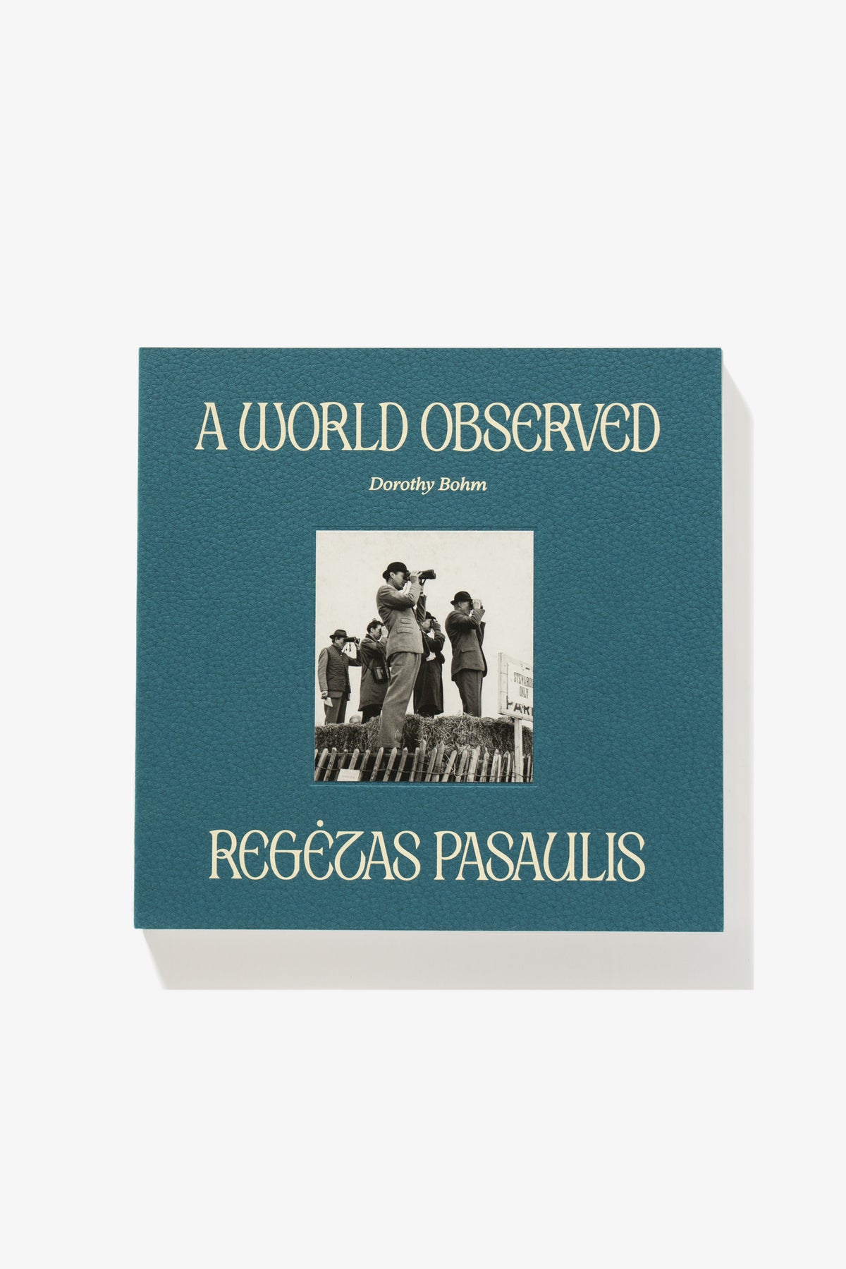 Full-length image of the cover of Dorothy Bohm’s A World Observed. Titles sandwich an image of a suited man peering into the distance through binoculars. The textured surface of the cover material is apparent.